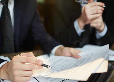 Business professionals reviewing and signing a legal contract 
during a meeting.