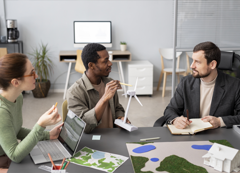 Team discussing sustainable architecture and renewable energy project with wind turbine model.